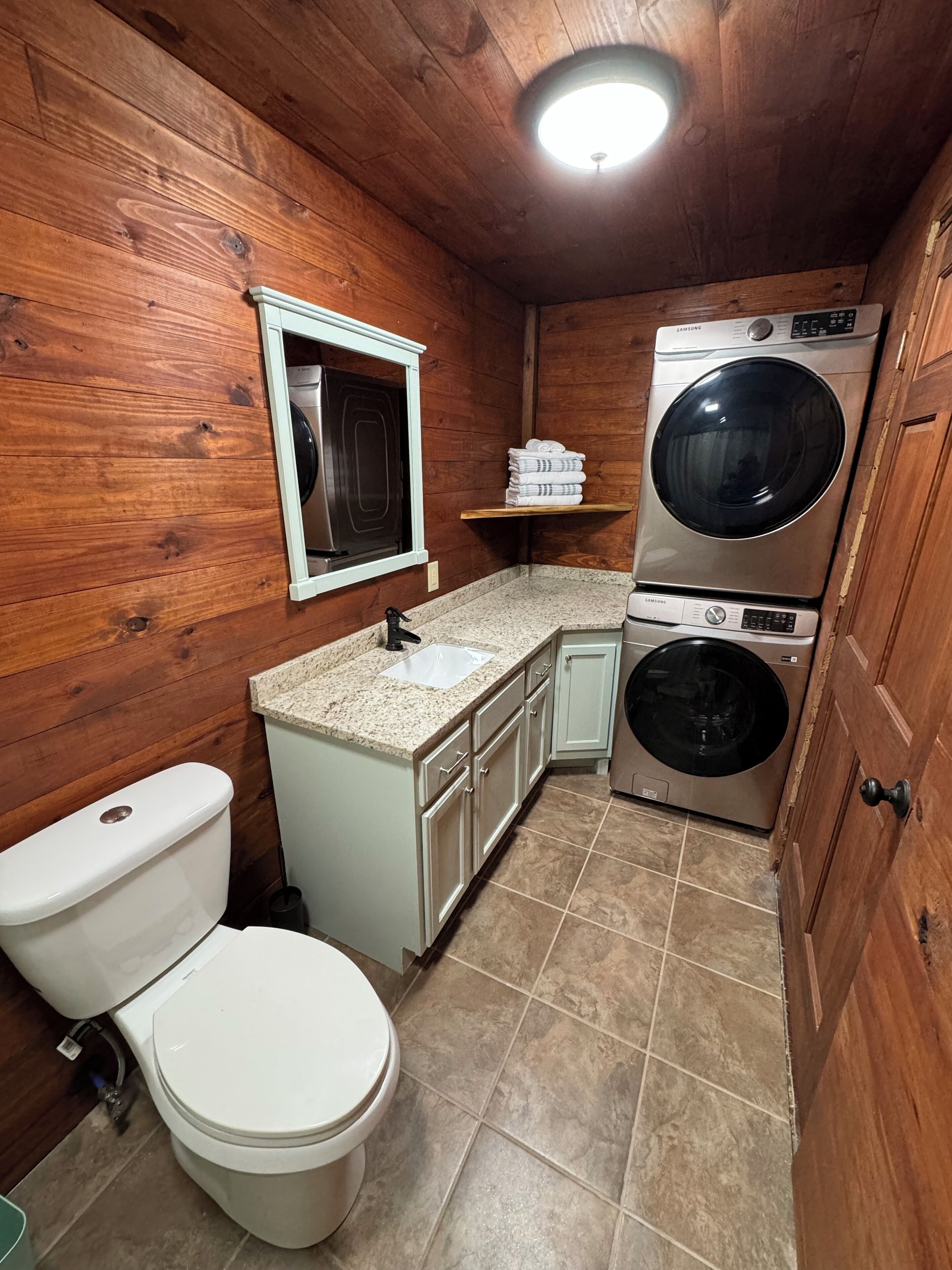 A compact bathroom with a toilet, sink, and stacked washer-dryer unit.