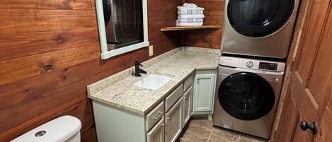 A compact bathroom with a toilet, sink, and stacked washer-dryer unit.