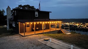 Una cabaña de madera con porche, chimenea y una bandera estadounidense.