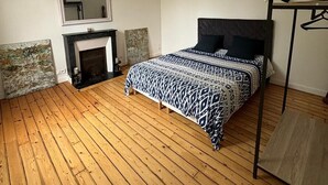 Une chambre à coucher avec un lit, un fauteuil suspendu, une cheminée et un miroir.
