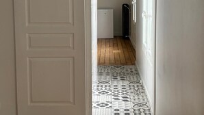 Un couloir avec une porte blanche, un radiateur et des carreaux de sol à motifs.