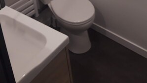 Un baño pequeño y funcional con inodoro, lavamanos y ventana sobre el inodoro.
