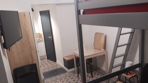 Una habitación pequeña con literas, un escritorio y una silla.