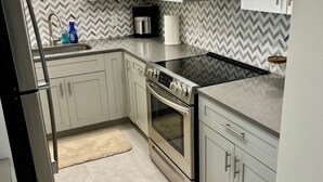 Una cocina moderna con armarios blancos, un refrigerador de acero inoxidable, un microondas y un horno.