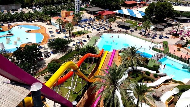 Ein Wasserpark mit mehreren Rutschen und Pools, umgeben von Palmen und Liegebereichen.