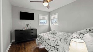 A bedroom with a bed, a ceiling fan, a TV mounted on the wall, and a dresser. - Cozy, Sunny, and Clean Apt 3 bd Free Parking (Berwyn)