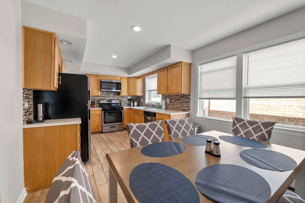 A modern kitchen with wooden cabinets, a black refrigerator, and a dining area with a table and chairs.