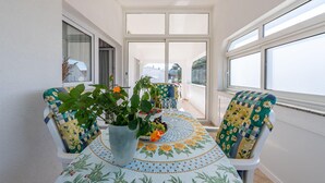Ein Balkon mit einem Tisch für zwei Personen, ausgestattet mit einer Tischdecke und Stühlen mit floralem Bezug.