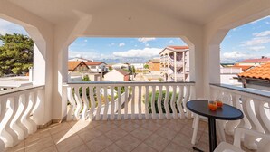 Ein Balkon mit Blick auf eine Stadt, ein Tisch mit zwei Gläsern und ein Stuhl.
