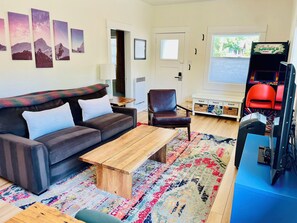 A living room with a sofa, armchair, coffee table, and a television.