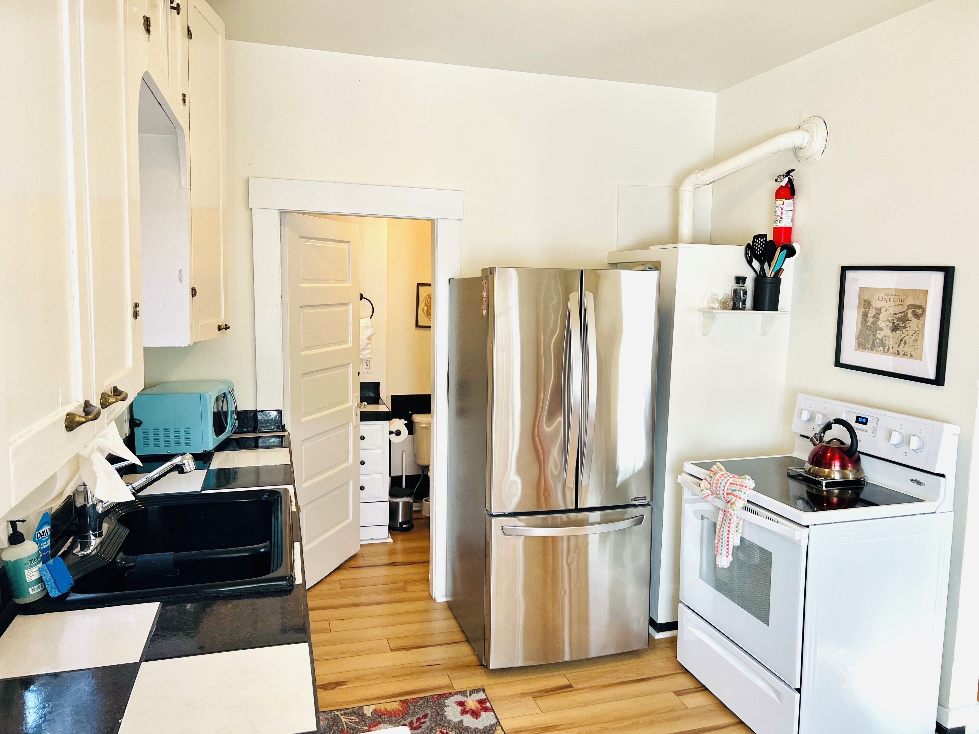 A compact kitchen with a stainless steel refrigerator, a white oven, and a microwave.