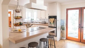 A modern kitchen with a large island, a built-in oven, and a water dispenser.