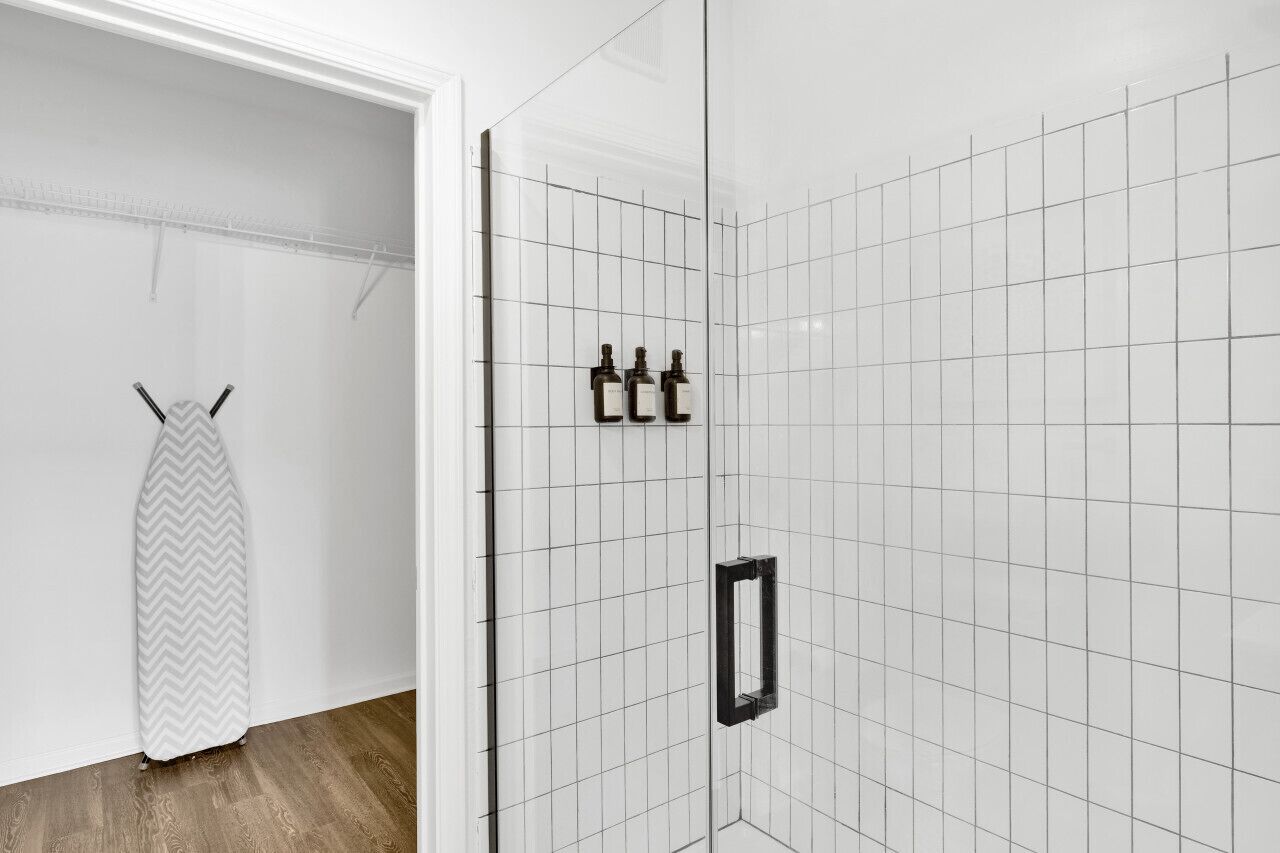 Een badkamer met witte betegelde wanden, een douchegedeelte en een handdoekhouder.
