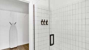 Een badkamer met witte betegelde wanden, een douchegedeelte en een handdoekhouder.