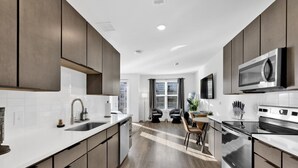 A modern kitchen with dark cabinets, white countertops, and stainless steel appliances. - Cozy Flat w/ Pool, Gym, & Stunning City Views (Birmingham)