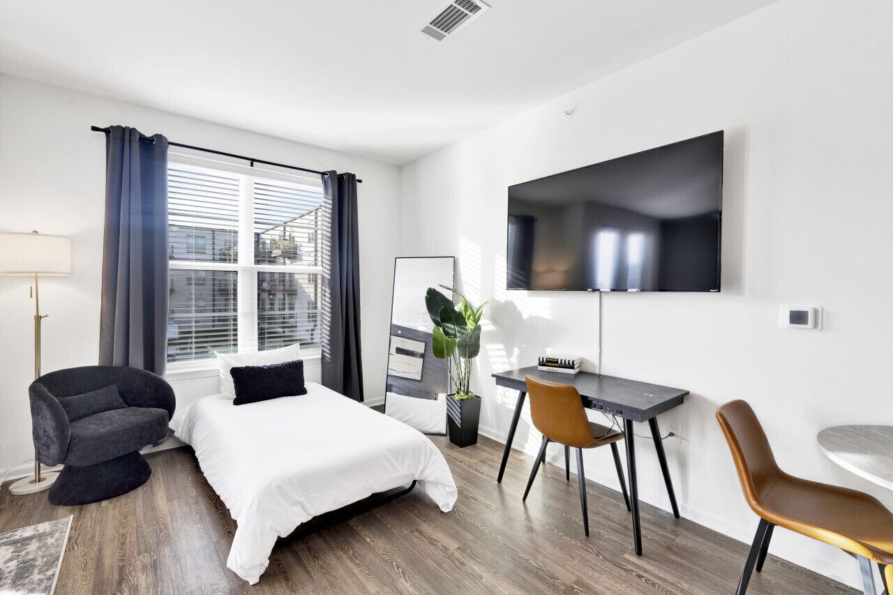 Ein modernes Hotelzimmer mit Bett, Schreibtisch und Fernseher.
