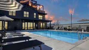 A modern building with a rooftop pool, lounge chairs, and umbrellas. - Cozy Flat w/ Pool, Gym, & Stunning City Views (Birmingham)