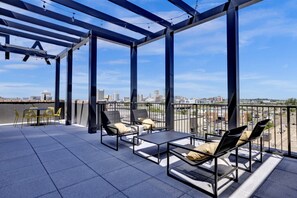 An outdoor terrace with metal-framed seating and a city view.