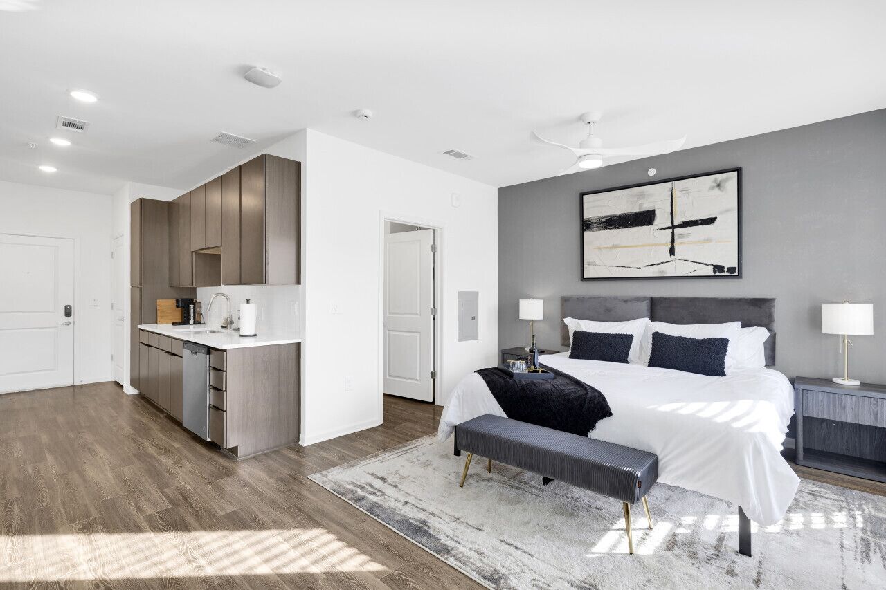 A modern bedroom with a large bed, bedside tables, and a grey accent wall.