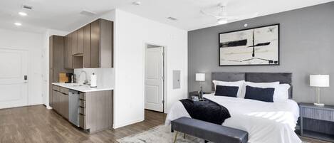 A modern bedroom with a large bed, bedside tables, and a grey accent wall.