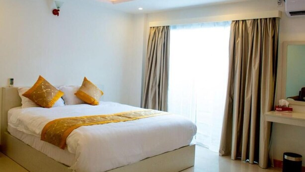 A hotel room with a bed, curtains, a ceiling fan, and a window. - Morus Bliss - Divers' Preferred Hotel (Hithadhoo)