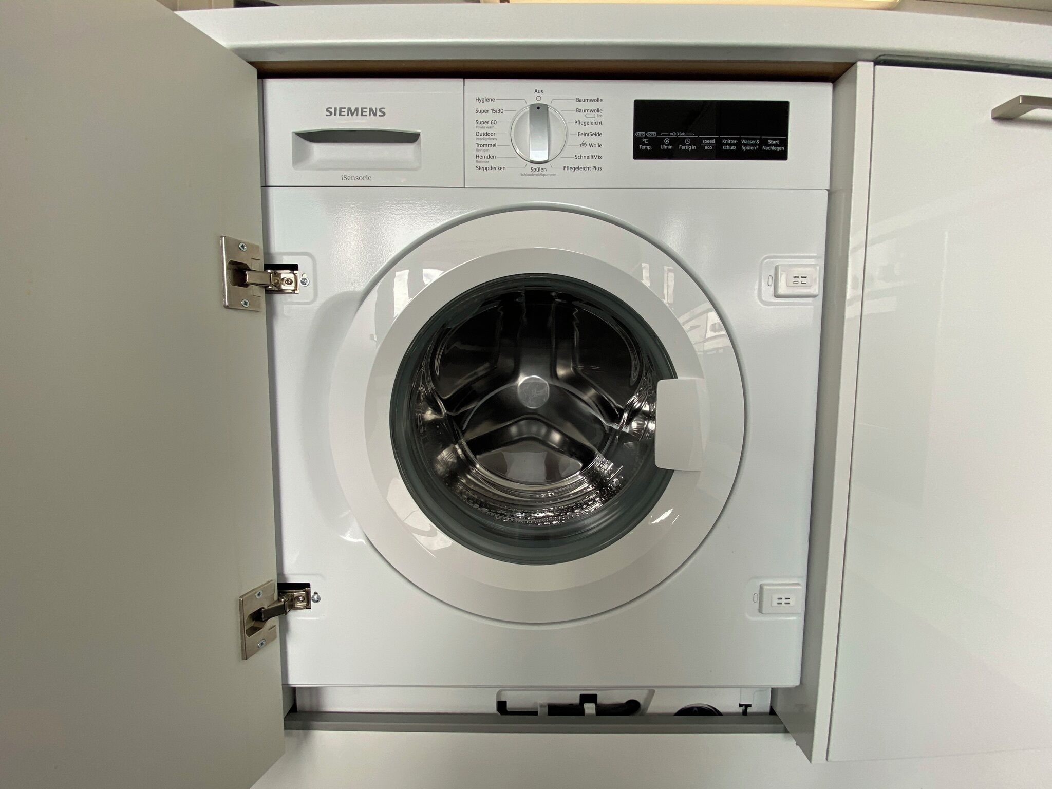 Una lavadora de carga frontal Siemens iSensoric con un panel de control que muestra varias opciones.