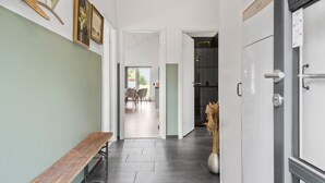 A hallway with a bench, a door with a sign, and a room with a shower. - 3 bedroom pet friendly home in ørsted (Ørsted)