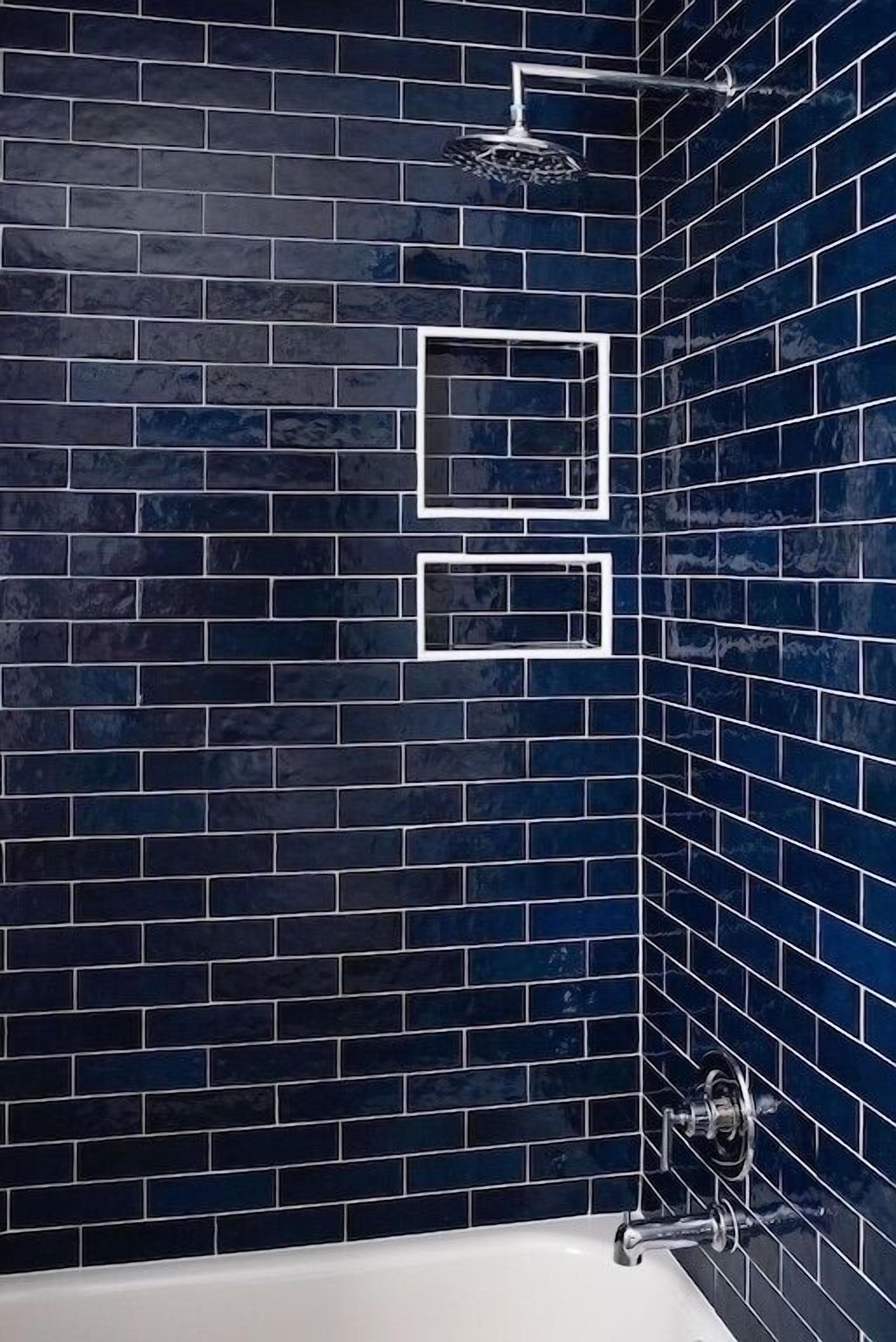 Een badkamer met donkerblauwe betegelde wanden en een witte badkuip.