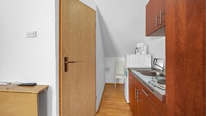 A compact kitchen with wooden cabinets, a white refrigerator, a coffee maker, and a stove.