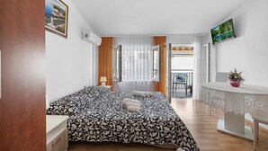A bedroom with a bed, a small table with a vase, and a balcony with a chair.