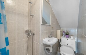 Een moderne badkamer met een douche, wastafel en toilet.