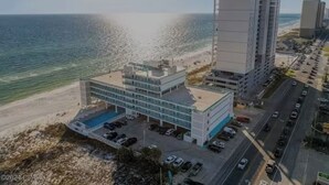 Ein modernes Hotel mit Pool in Strandnähe, im Hintergrund hohe Gebäude.