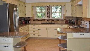 A kitchen with a refrigerator, stove, sink, and two bar stools. - Updated farmhouse on 5 acres near salem oregon (Jefferson)