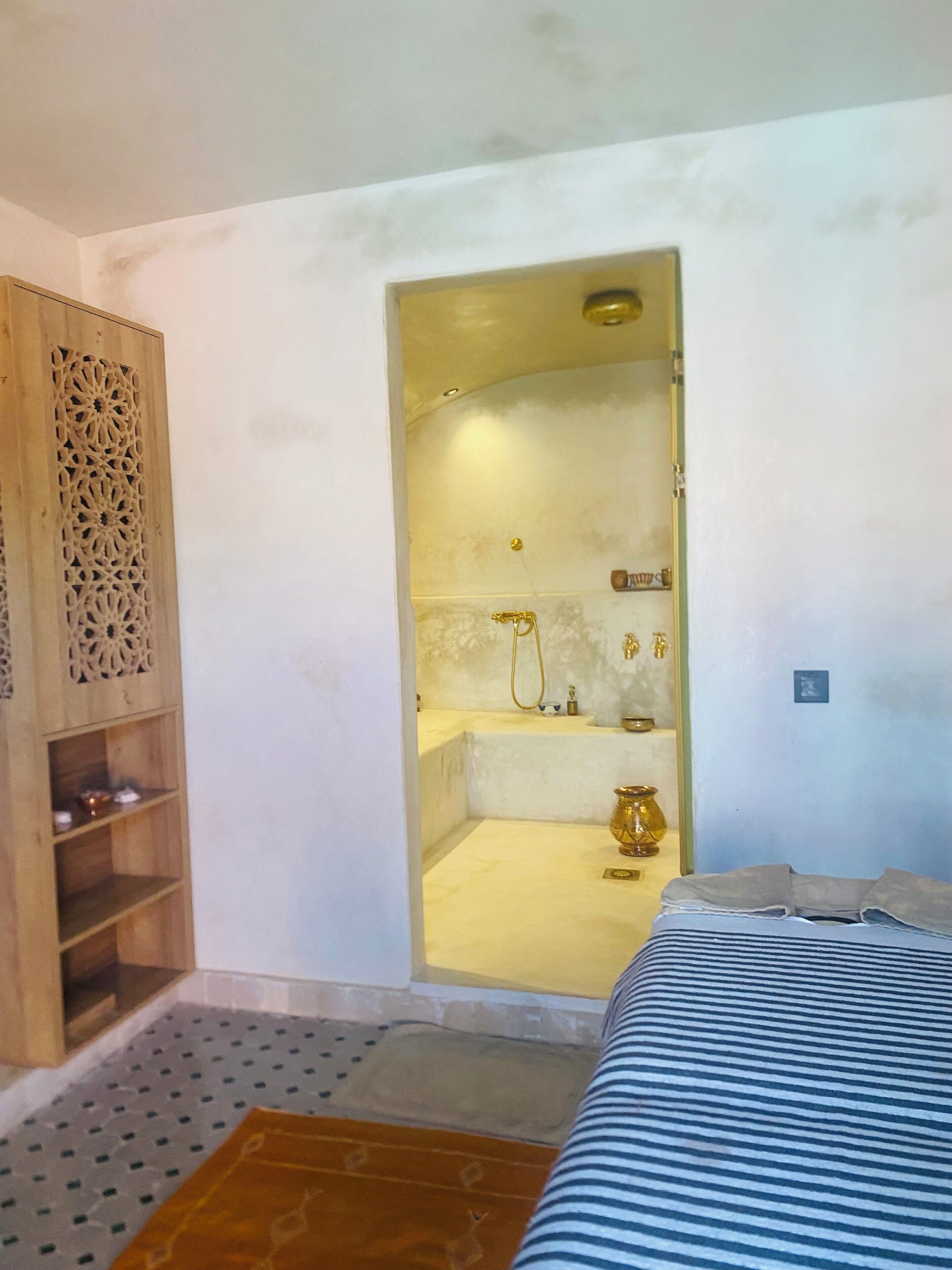 A room with a bed, a wooden cabinet, and a shower area.