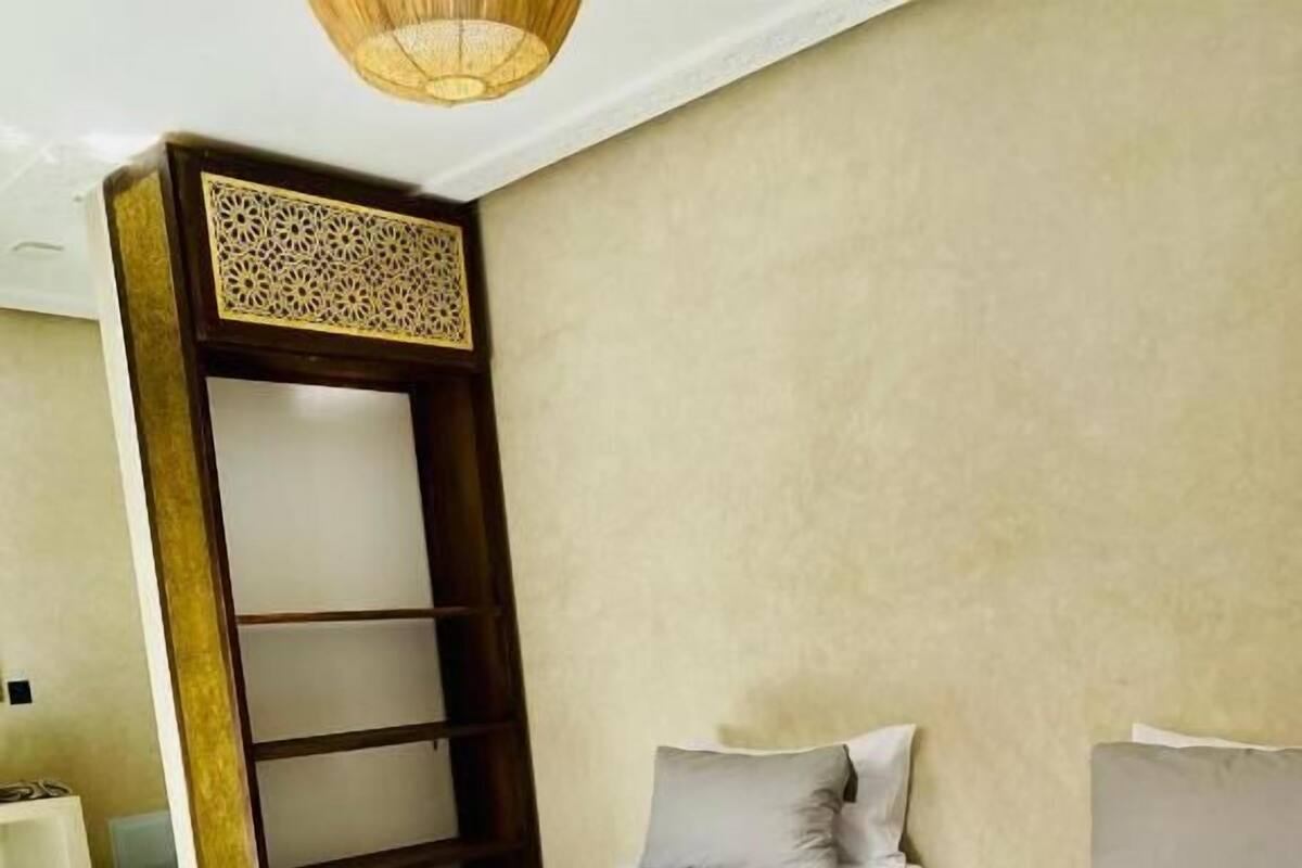 Une chambre avec deux lits, une étagère en bois et un sol à motifs.
