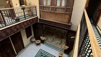 Un patio con piscina, mobiliario de madera y detalles arquitectónicos elaborados.