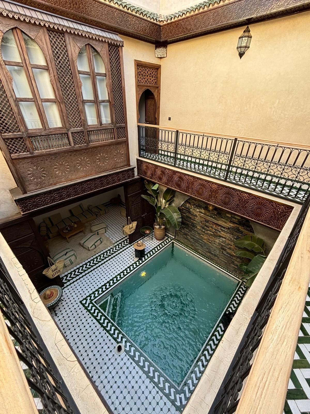 Un patio con piscina, puertas de madera ornamentadas y suelo de baldosas.