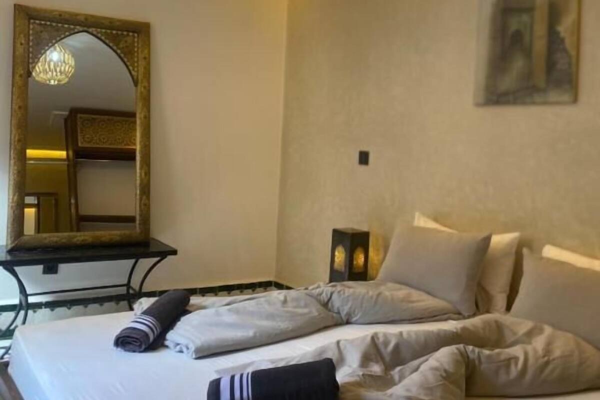 Une chambre d’hôtel avec un lit, un miroir, un tableau et un lustre.