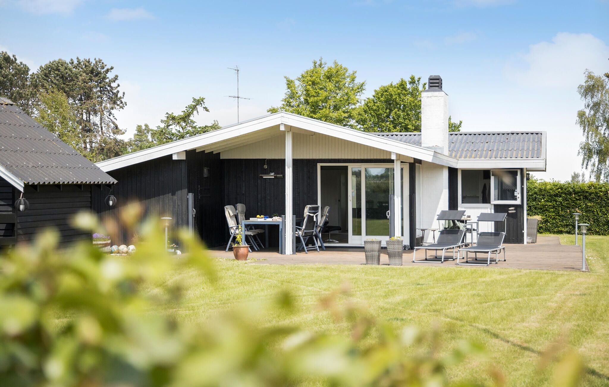 A modern house with a covered patio, a dining area, and a large chimney.