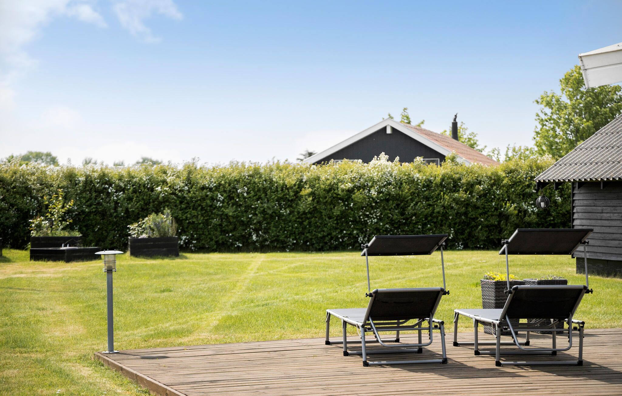 A wooden deck with three lounge chairs and a metal lamp post.