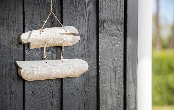 Ein hölzernes Schild mit der Aufschrift "Gone to the beach" und "The beach" an einer schwarzen Holztür.