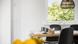 A dining area with a wooden table, black chairs, and a window with a view of greenery. - 3 bedroom lovely home in Otterup (Otterup)