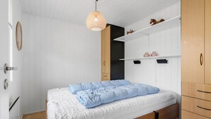 A bedroom with a bed, wooden wardrobe, and a hanging light fixture. - 3 bedroom lovely home in Otterup (Otterup)
