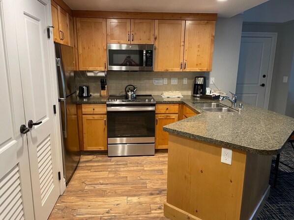 A kitchen with wooden cabinets, stainless steel appliances, a granite countertop, and a built-in island.