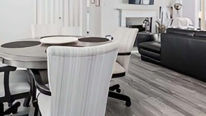 Un salon moderne comprenant une table à manger, des chaises, un canapé et un téléviseur.