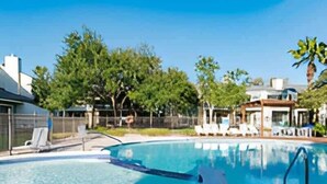Une piscine à bord incurvé, entourée de chaises longues et dotée d’un espace abrité.