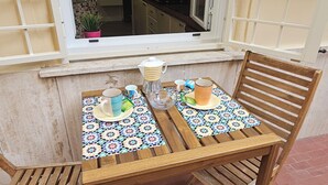 A wooden table with a tiled tablecloth, two chairs, and a window with a view into a kitchen. - 2 bedroom apartment in rome (Roma)