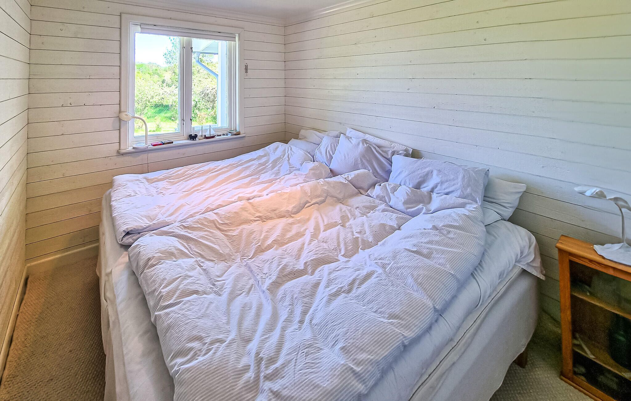 Ein Schlafzimmer mit einem Bett, einem Fenster und einem Nachttisch.