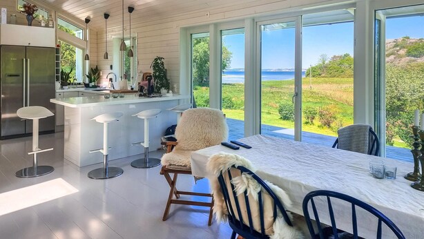 A modern kitchen with a central island, bar stools, and a view of the ocean.