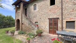 Un edificio de piedra con puerta de madera, una ventana y un pequeño balcón.